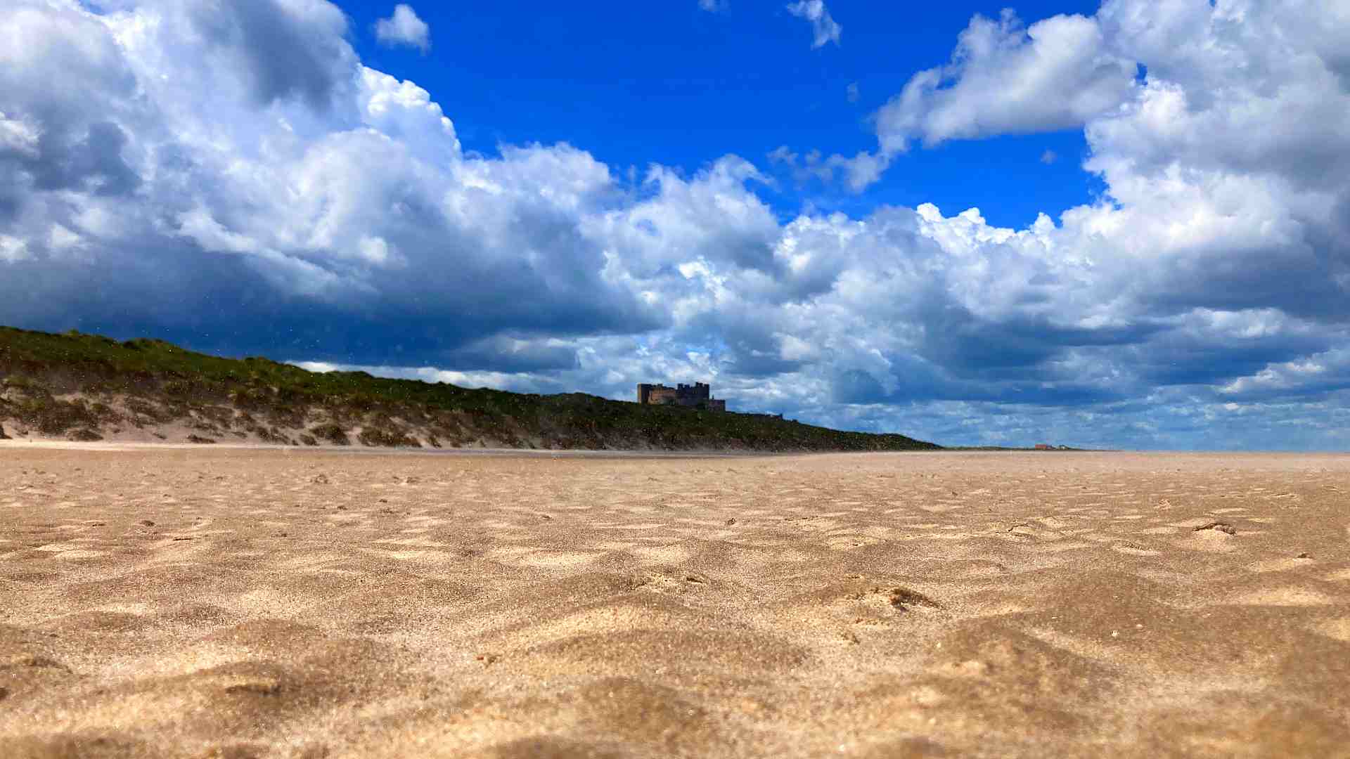 Sandy beach under a cloudy sky near bamburgh castle.
